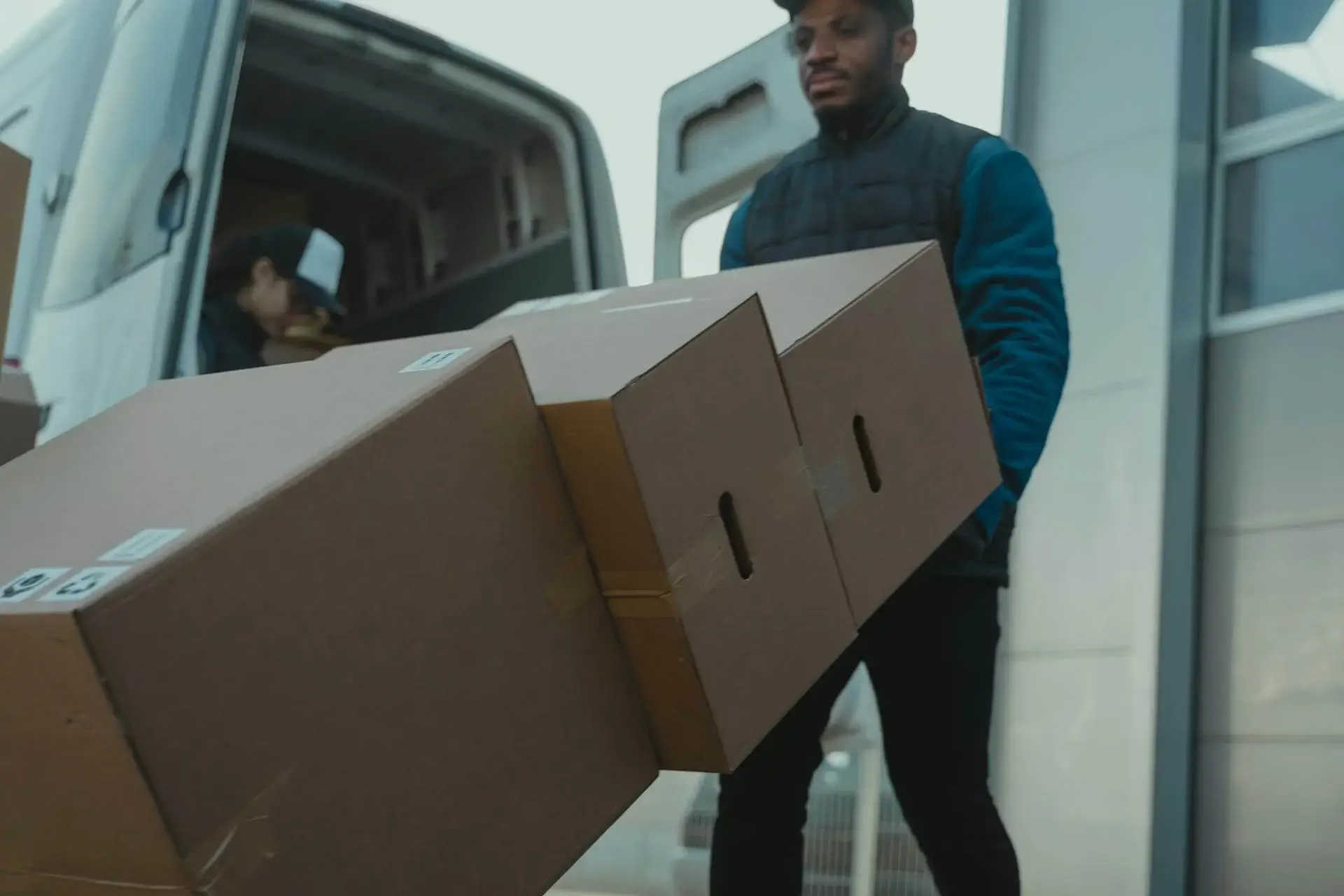 a man pulling a cart with 3 packages to put inside the car